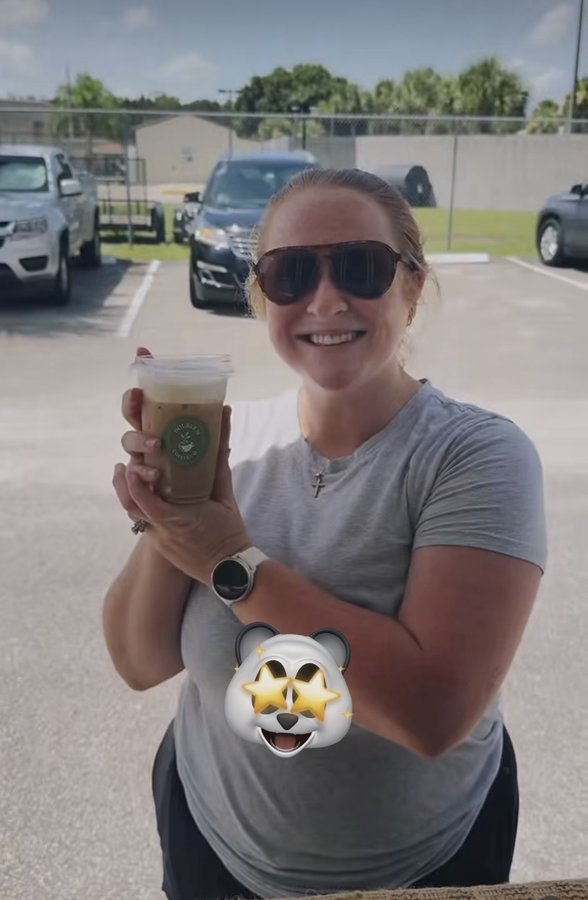 Customer holding a Double H Coffee Co. iced coffee, smiling outdoors